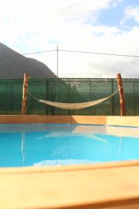a swimming pool with a hammock and a fence at Cabaña Alpina SEAL in Oxapampa
