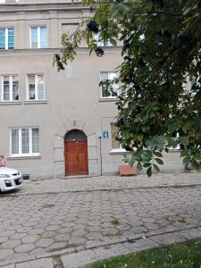 un edificio con una puerta roja y un coche aparcado delante en Apartament Glamour Chełm en Chełm