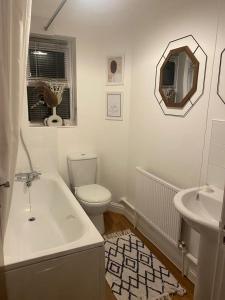 a bathroom with a tub and a toilet and a sink at Acacia Villa in Dunstable