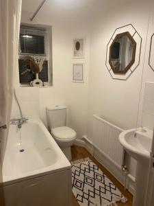 a bathroom with a tub and a toilet and a sink at Cosy 2 Bedroom House in Dunstable