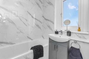 a white bathroom with a sink and a mirror at Modern & Spacious 2 Bedroom House - Free Parking - Front & Back Garden - Private Main Door Entrance in Edinburgh