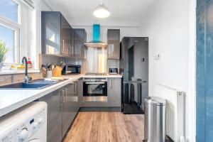 a kitchen with stainless steel appliances and wooden floors at Modern & Spacious 2 Bedroom House - Free Parking - Front & Back Garden - Private Main Door Entrance in Edinburgh