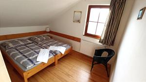 um quarto com uma cama, uma cadeira e uma janela em Penzion Vanda em Velké Pavlovice