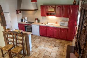 a kitchen with red cabinets and a sink at La grange Mirabelle in Rueil-la-Gadelière +7 photos