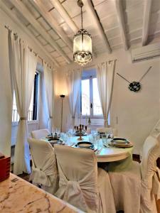 een eettafel met witte stoelen en een kroonluchter bij Monserrato Apartment in Rome