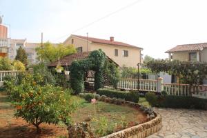 einen Garten mit einem Bogen und Orangenbäumen und ein Haus in der Unterkunft Lily's lovely apartments in Fažana