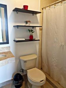 y baño con aseo y cortina de ducha. en Departamento de dos habitaciones con increíble alberca y amenidades Y-406 en Cancún