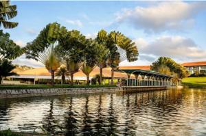 eine Brücke über einen Fluss mit Palmen und Gebäuden in der Unterkunft Villa Hípica Resort- Flat 203 in Gravatá