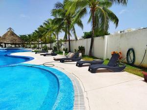 una piscina con tumbonas y palmeras en Departamento de dos habitaciones con increíble alberca y amenidades Y-406 en Cancún