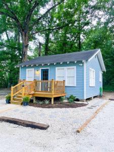 a small blue tiny house with a wooden porch at Unwind & Relax at Azalea Cottage on Bayou in Lafayette