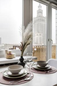 a dining room table with plates and glasses and a window at Apartments Centre by Arrenda in Warsaw