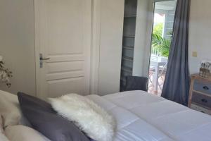 ein weißes Bett mit einem pelzigen Kissen darüber in der Unterkunft Le Petit Saint-Barth in Baie-Mahault
