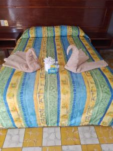 Una cama con toallas y zapatillas. en Hotel Verasol, en Veracruz