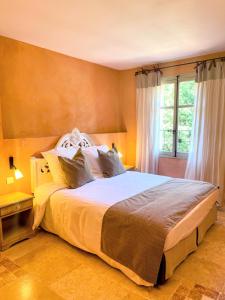 a bedroom with a large bed and a window at Hôtel Le Mas des Grès & Restaurant Sous les Platanes in Lagnes