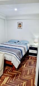 a bedroom with a bed and a night stand with a lamp at Hospedaje apus in Huaraz