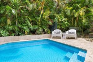 a swimming pool with two lawn chairs next to at Pavilion 5 in Byron Bay