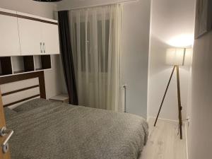 a bedroom with a bed and a window and a lamp at Sunny Prishtina Apartment in Pristina