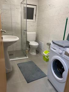 a bathroom with a washing machine and a toilet at Sunny Prishtina Apartment in Pristina +5 photos