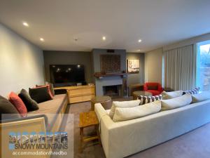 a living room with two couches and a television at Snowman 1 in Thredbo