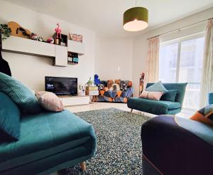 a living room with two blue couches and a tv at Your Room, Your Apartment, Your Shared Pool in Marsalforn
