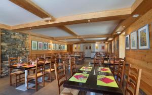 een restaurant met houten muren en tafels en stoelen bij Les Roches 1500 in Mieussy