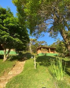 a garden with trees and a house in the background at Chalés Canto da Serra in Conceição da Ibitipoca