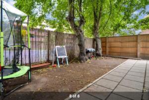 a backyard with a tree and a swing set at London Holiday Home - Entire 4 Bedroom Private House with Kitchen, Living Room & private Garden - 1 Cape House London, Within 30 mins from Central London, London Bridge & Canary wharf in London