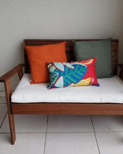 a wooden bench with two pillows on it at Apto beira-mar pé na areia in Barra Velha