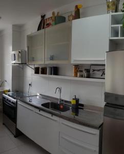 a kitchen with white cabinets and a sink and a stove at Apto beira-mar pé na areia in Barra Velha