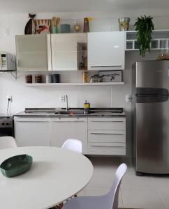 eine Küche mit weißen Schränken, einem Tisch und einem Kühlschrank in der Unterkunft Apto beira-mar pé na areia in Barra Velha