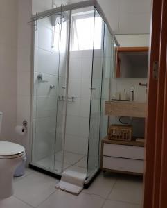 ein Badezimmer mit Glasdusche und Toilette in der Unterkunft Apto beira-mar pé na areia in Barra Velha
