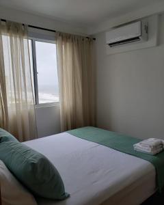 a bedroom with a large bed with a window at Apto beira-mar pé na areia in Barra Velha