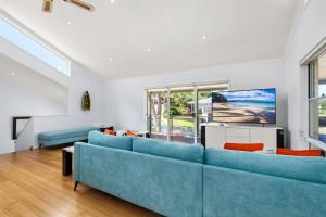 a living room with two blue couches and a tv at Tuncurry Close 1A in Nelson Bay