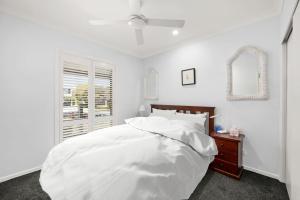 a white bedroom with a bed and a window at Tuncurry Close 1A in Nelson Bay