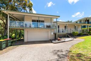 a house with a balcony and a garage at Tuncurry Close 1A in Nelson Bay