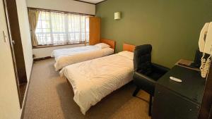 a bedroom with two beds and a desk with a phone at irodori in Matsumoto