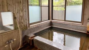 a pool of water in a bathroom with windows at irodori in Matsumoto