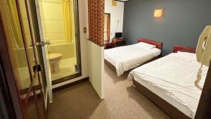 a room with two beds and a bathroom with a toilet at irodori in Matsumoto