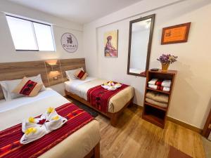 a hotel room with two beds and a mirror at Runas Inn Machupicchu in Machu Picchu