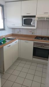 a kitchen with white cabinets and a microwave at San Alfonso del Mar Goleta 307 in San Antonio