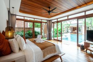 a bedroom with a bed and a tv and a pool at Paya Paya Villa Seminyak in Seminyak