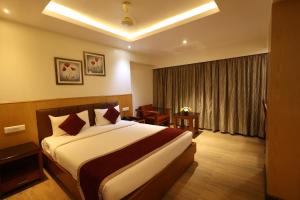 a hotel room with a large bed and a desk at Akash Inn in Shimoga