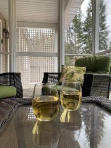 dos copas de vino sentadas en una mesa de cristal en Modern 4 season cottage retreat en Huntsville