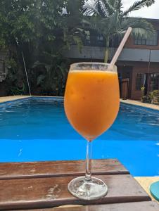 a glass of orange juice sitting on a table near a swimming pool at Departamento Iguazú Cataratas in Puerto Iguazú