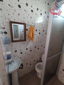Namaste Hostel في تاريخا: حمام مع مرحاض ومغسلة مع أوراق على الحائط