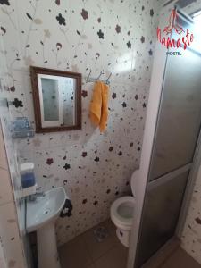 a bathroom with a toilet and a sink with leaves on the wall at Namaste Hostel in Tarija