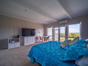 sypialnia z niebieskim łóżkiem i balkonem w obiekcie 1-bedroom unit with balcony and ocean views! w mieście Smiths Beach