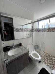 y baño con aseo, lavabo y espejo. en Habitación Principal en Apto Compartido piso 26, en Bucaramanga