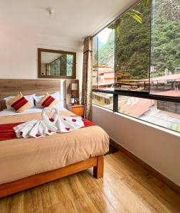 a bedroom with two beds and a large window at Runas Inn Machupicchu in Machu Picchu