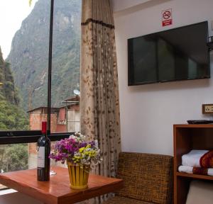 Habitación con ventana, botella de vino y flores en Runas Inn Machupicchu en Machu Picchu